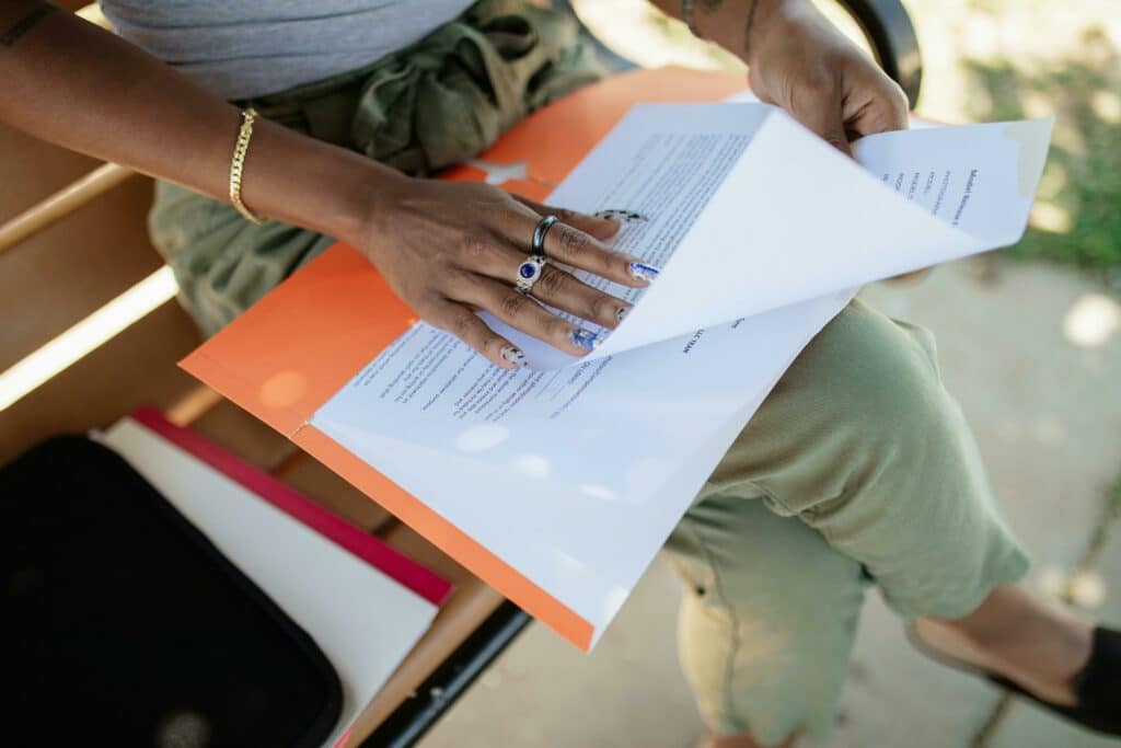 Main de praticienne consultant un dossier d'inscription pour devenir auto-entrepreneur dans le bien-être