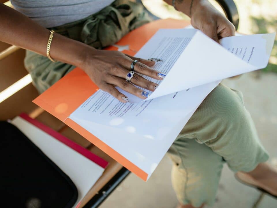 Main de praticienne consultant un dossier d'inscription pour devenir auto-entrepreneur dans le bien-être
