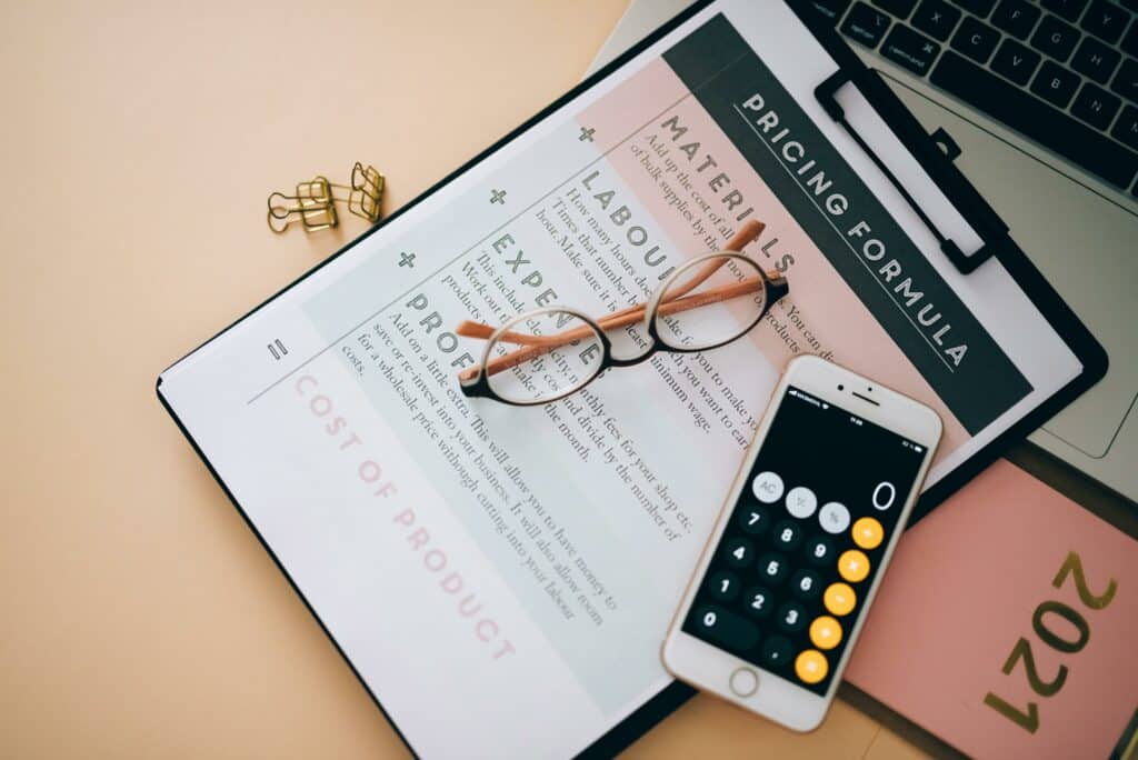 Photo qui représente la fixation d’un prix avec une fiche de calcul et un téléphone portable