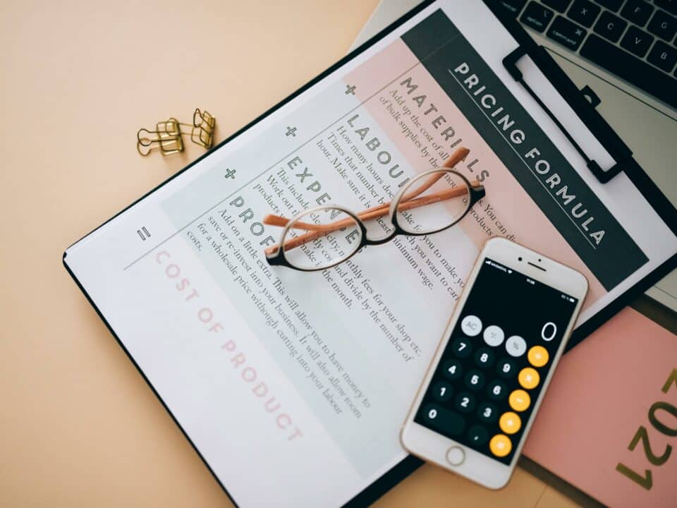 Photo qui représente la fixation d’un prix avec une fiche de calcul et un téléphone portable