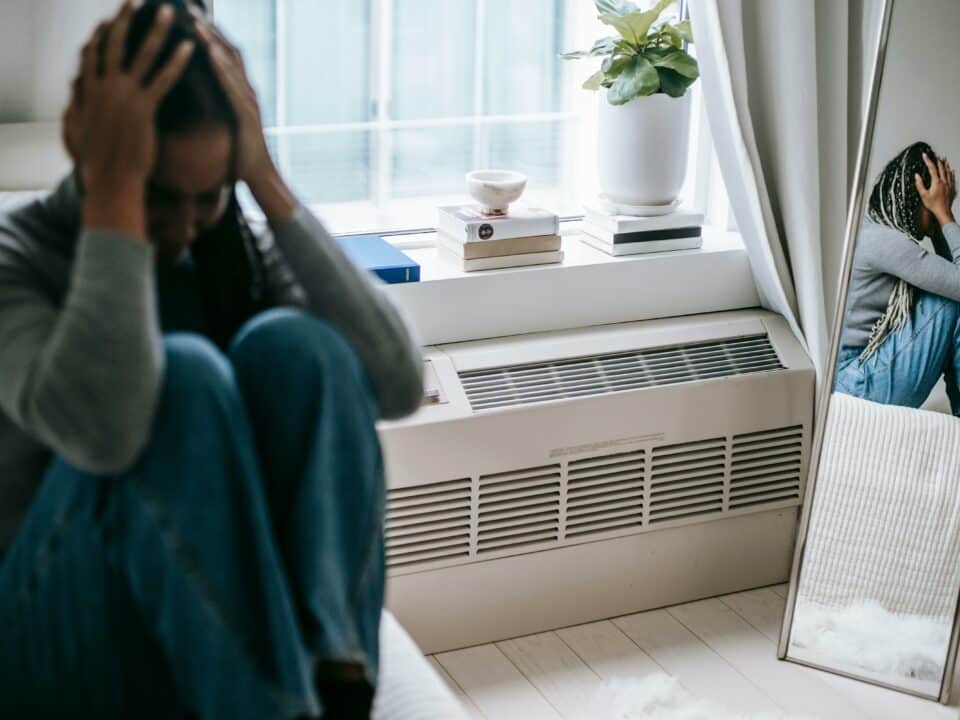 Personne assise, tête dans les mains, illustrant le stress chronique et la surcharge du système nerveux