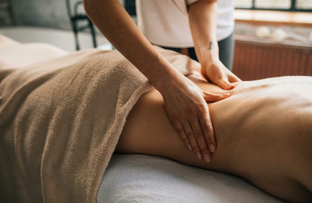 Mains d’un praticien réalisant un massage bien-être sur une personne allongée